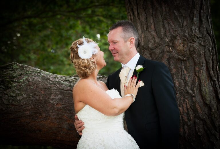 Bride and groom embracing by a tree