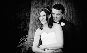 bride and groom cuddling by a tree at Wentworth