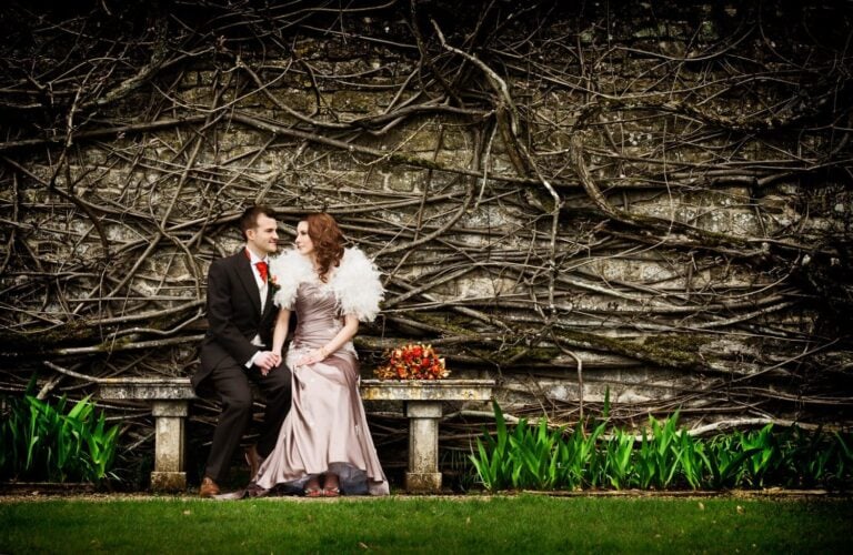 Bride and groom on a bench against a vine wall