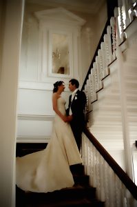 Bride and Groom have a romantic encounter on a grand stair case at warbrook Park