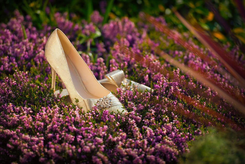 Silver wedding shoes on heather in bloom