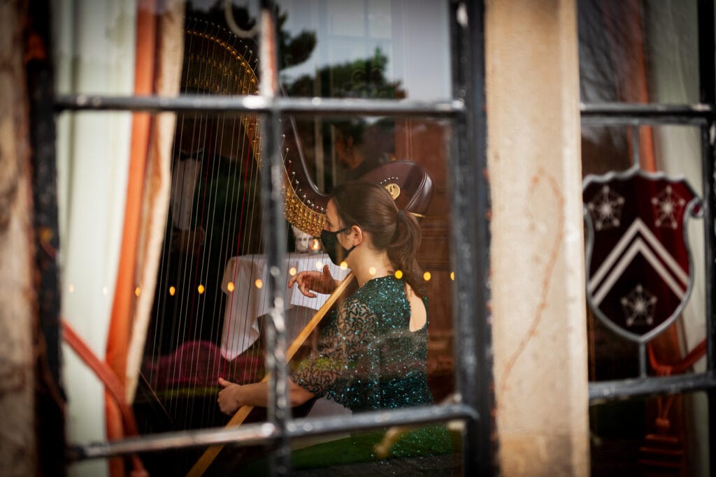 Looking through an old window onto a harpist playing