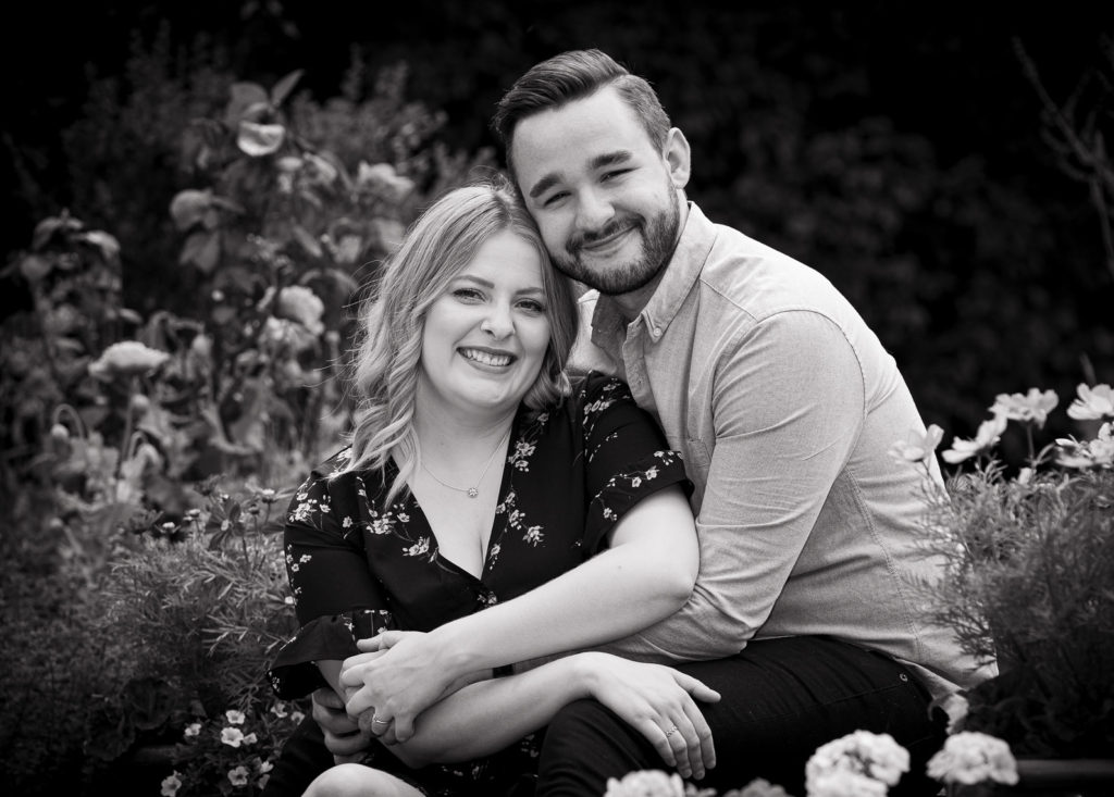 Black and white engagement of a couple sitting on the steps in a garden