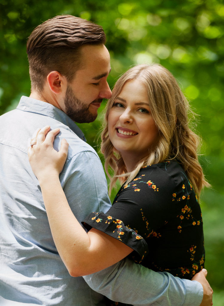 Engagement shoot of a couple. Girl looking back over mans shoulder