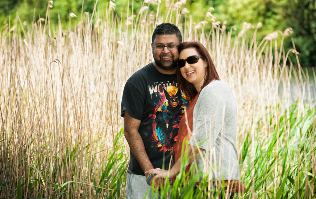 Couple holding hands with a pond and reeds in the background