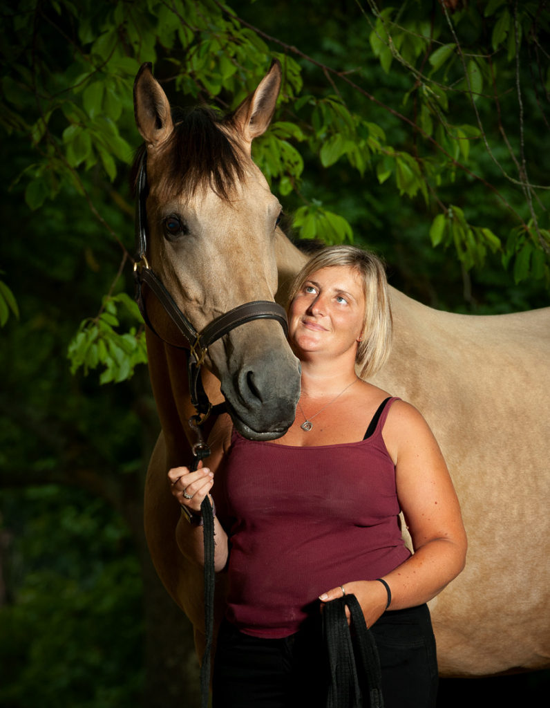 Girl and her horse portrait lit with studio lighting under a tree