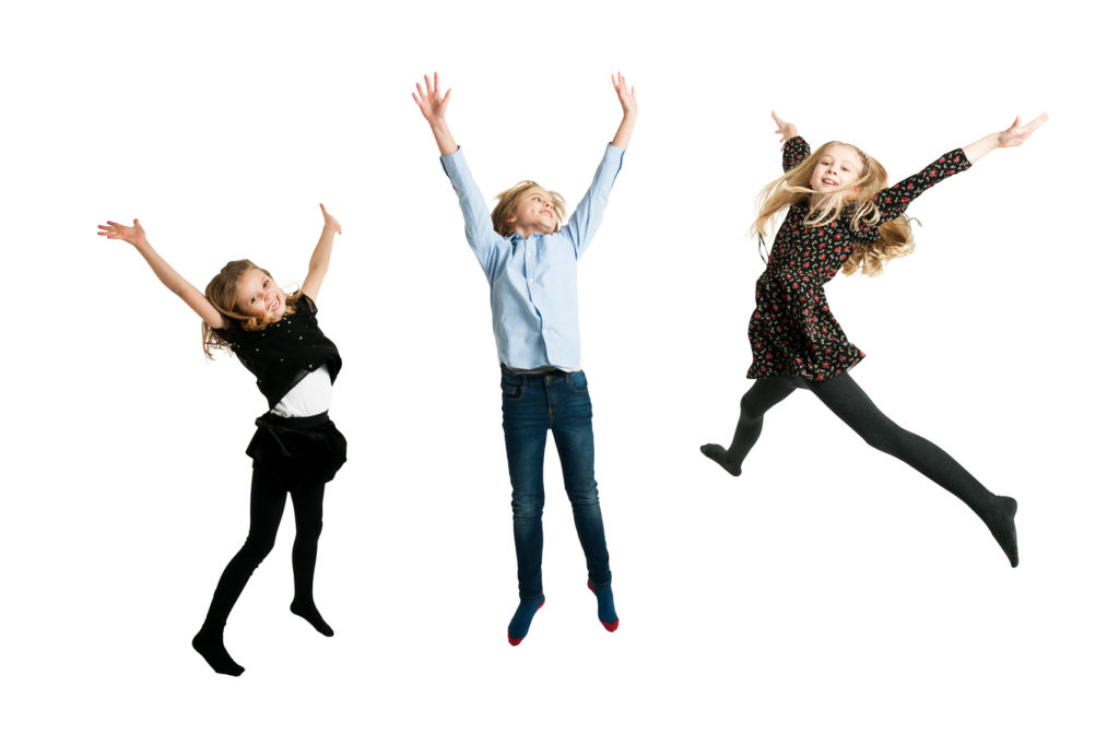 3 children leaping in the air. Studio portrait against a white background.